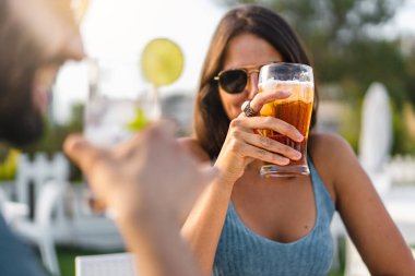 Neşeli genç arkadaşlar konuşuyor ve içiyor. Yaz kaldırımındaki bir barda oturup eğleniyorlar. Yemek, içki ve insanların yaşam tarzı konsepti.