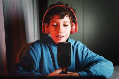Küçük vlogger özentisi - odasında mikrofonla konuşan ve sosyal videosunu kaydeden çocuk - teknoloji ve insan yaşam tarzı kavramı