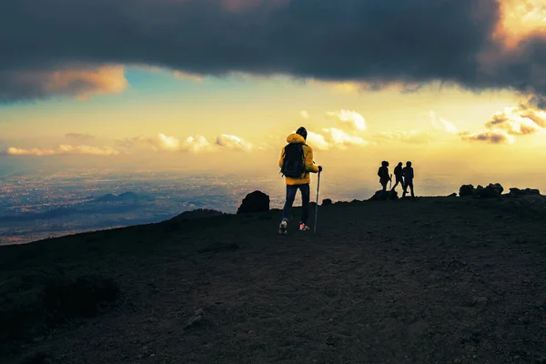 一群徒步旅行者在日落时分走过意大利西西里Etna山的熔岩 那些难以辨认的人 从后面的云天中看到 人们的生活方式的概念 — 图库照片