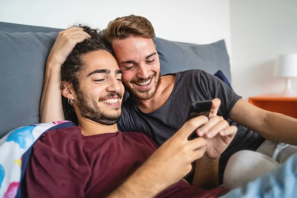 情投意合的同性恋夫妇在网上看内容与手机在床上 同性恋的人保持在一起使用智能手机 Lftb文化和人的生活方式概念 — 图库照片