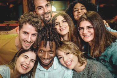 8 gülümseyen ve mutlu çok kültürlü genç insanın bir grup fotoğrafı için kafalarını bir araya toplarken çekilmiş yakın plan portresi..