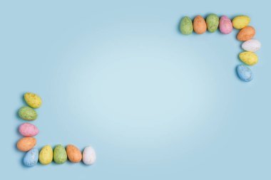 Paskalya temalı pastel mavi arka planında köşeleri şekillendiren renkli Paskalya yumurtaları yer alıyor. İnternet pankartları, tebrik kartları, sosyal medya paylaşımları ve daha fazlası için mükemmel