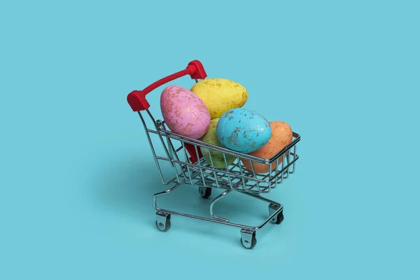 Renkli Paskalya Yumurtalarıyla Dolu Bir Alışveriş Arabası Pastel Mavi Arka — Stok fotoğraf