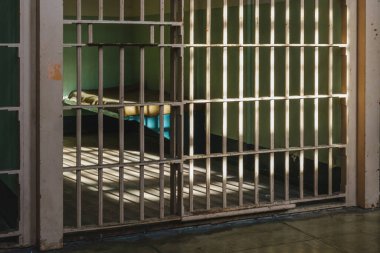 Alcatraz Adası, San Francisco, ABD - 24 Aralık 2022: Alcatraz 'da yataklı karanlık hapishane hücresi, demir parmaklıklar ve filtrelenmiş ışık odaya giriyor, tarihi kent simgesi ve eski federal cezaevi.