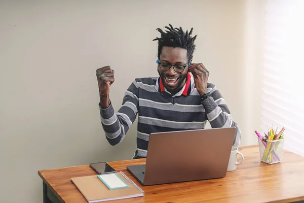Afroamerykanin Krótkimi Dredami Niebieskimi Słuchawkami Bezprzewodowymi Świętuje Sukces Przed Ekranem — Zdjęcie stockowe