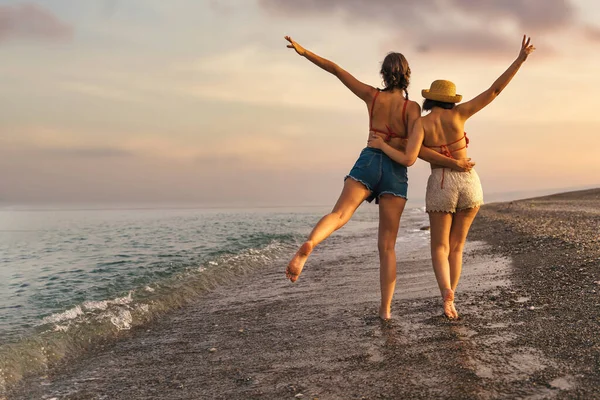 Δύο Νεαροί Φίλοι Ένας Ψάθινο Καπέλο Περπατούν Στην Παραλία Ηλιοβασίλεμα — Φωτογραφία Αρχείου