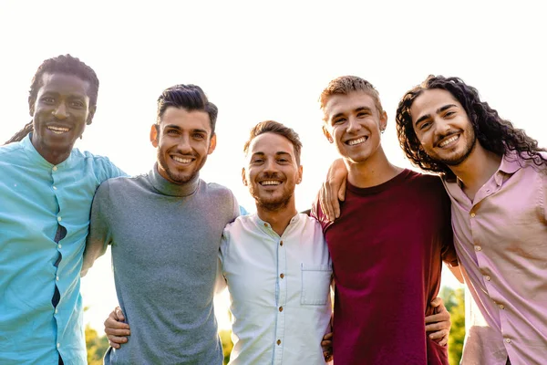 由5名男性朋友组成的多种族小组在户外拥抱 分享团结和欢乐的时刻 他们都面带微笑 把愉快的表情对准摄像机 — 免费的图库照片