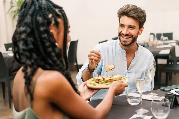 A smiling young man shares a meal with a woman at a contemporary dining setting, highlighting a relaxed and enjoyable lunch date. Best friends enjoying food.