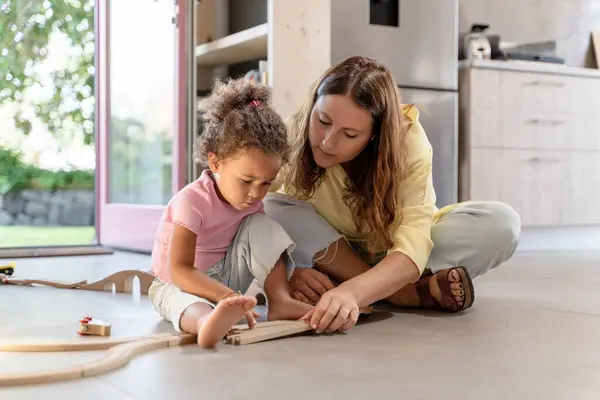 おもちゃトレインで遊ぶ母と子供 母と娘は木製の列車セット 家族との絆と遊び心のある学習の心温まるシーンを組み立てます — ストック写真
