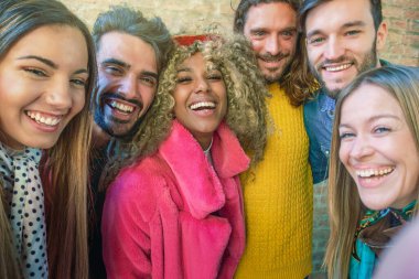 Bir grup arkadaş gülüyor ve selfie çekiyor, neşe ve arkadaşlık yayıyorlar..