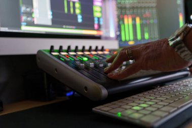 Ses mühendisinin eli ses karıştırma konsolunda kaydırıcıları ayarlıyor, müzik üretiminin teknik tarafını gösteriyor ve hassasiyeti karıştırıyor..
