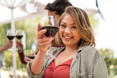 Işıl ışıl bir kadın kadeh kaldırmak için kadehini kaldırır. Gülüşü bu anın neşesini yansıtır..