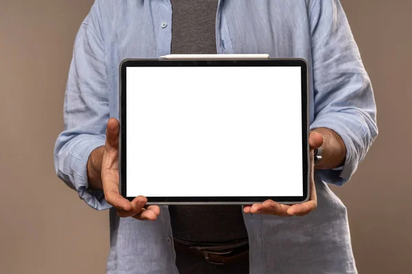 A businessman holding a tablet with a blank screen, ready for mockup presentations, isolated on a neutral background.
