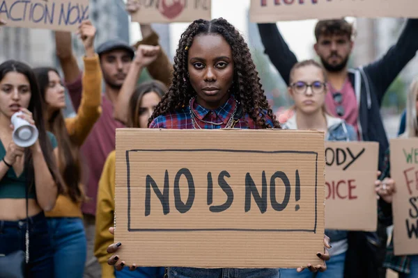 Young woman firmly holding a \'No Is No\' sign, symbolizing empowerment at a feminist rally