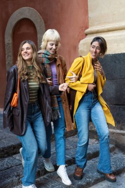 Bir grup arkadaş, eşsiz tarzlarını ve arkadaşlıklarının sıcaklığını sergileyerek tarihi şehir merdivenlerinden canlı bir şekilde iniyor..