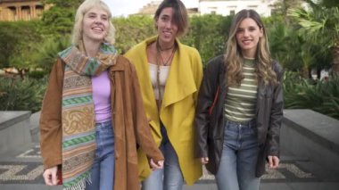 Üç kadın, yemyeşil bir parktaki basamaklara tırmanıyor. Konuşmaları, etraflarındaki doğal ortam kadar canlı. Boş vakit ve dostluk dolu bir öğleden sonrayı vurguluyorlar..