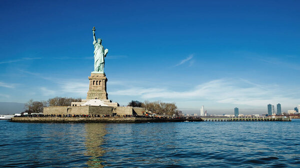 The Statue of Liberty stands tall against the backdrop of the Manhattan skyline, symbolizing American freedom.