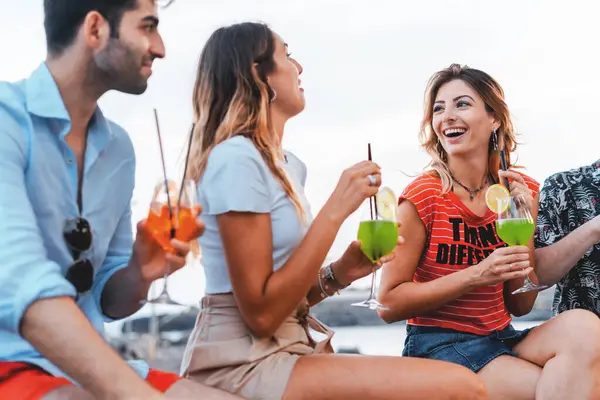 Friends share a joyful moment with cocktails - Laughter and bonding in a casual setting - Enjoying summer vibes with refreshing drinks.