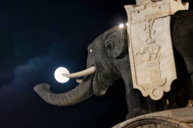 Catania 'daki fil heykeli. Dolunay, şehrin tarihi sembolü, mimari güzelliği ve gece manzarası tarafından tutuluyormuş gibi görünüyor..