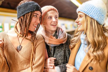 Halka açık bir ortamda canlı sohbetin tadını çıkaran farklı etnik kökenlere sahip üç şık genç kadın. Görüntü, gerçek duygular ve bağlantılar sergilerken, çeşitlilik, dostluk ve kış modasını yakalar..