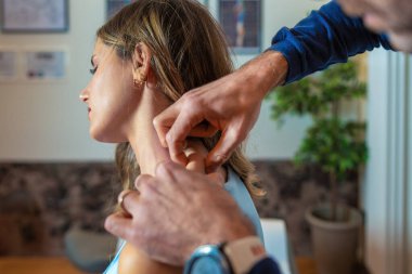 Profesyonel bir manüel terapi seansı sırasında bir osteopatın kadın hastasının boynunu tedavi ettiği fotoğraf. Alternatif tıpta nazik manipülasyon teknikleri ve kişisel bakım gösteriyor.