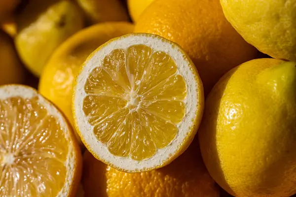 Taze limonların Macro manzarası, hem dilimlenmiş hem de tek parça. Canlı sarı turunçgiller sulu hamurlar ve kabuklu dokular sergiliyor. Yemek, içecek ve aromaterapi için doğal, sağlıklı bir malzeme..