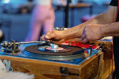 DJ 'lerin ellerini ahşap çantalı vinil pikabın üzerine koyun. Profesyonel müzik ekipmanları iş başında. Parti veya kulüp etkinliğinde klasik analog ses ayarı.