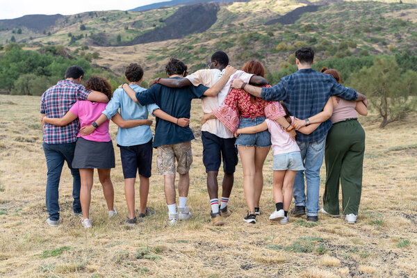 Generation Z friends showing unity and inclusion in nature. Rear view of diverse community group demonstrating authentic connection and belonging together