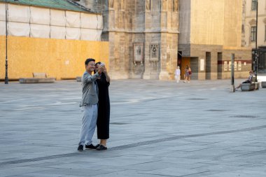 VIENNA, AUSTRIA - AUGUST 11, 2024: Tourist couple takes selfie in front of St. Stephen's Cathedral at Stephansplatz. Modern tourism meets historic architecture in city center clipart