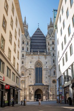 Vienna, AUSTRIA - 8 Ağustos 2024: St. Stephen 's Katedrali Gotik cephesi tarihi merkezdeki dar sokaktan görülüyor. Modern binalar tarafından çerçevelenmiş ortaçağ kilise mimarisi kentsel karşıtlığı gösteriyor