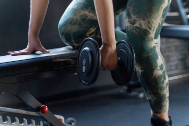 Dambıl sırası egzersizi için uygun form ve ekipman çekimleri. Modern fitness eğitimi çağdaş spor salonunda şık kravat boyası aktif giyimli tekniğe dikkat gösteriyor.