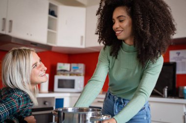 Modern mutfakta birlikte yemek yapan iki farklı genç bayan arkadaş, Afro-Amerikan ve Kafkasyalı oda arkadaşları ev hayatını paylaştılar.