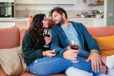 Genç çiftin koltukta sevgisini ifade ettiği otantik bir an. Çağdaş oturma odasındaki doğal ve spontane etkileşim gerçek ilişkiyi gösteriyor..