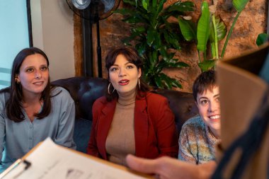 Garson, rahat bir kafede bir grup gülümseyen kadından kahve siparişi alıyor..