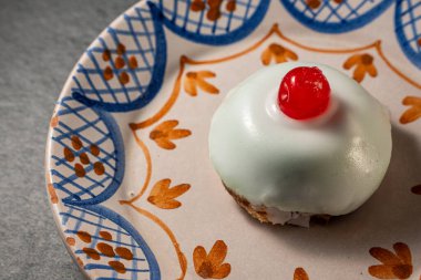 Geleneksel Sicilya cassata pastasına yakın plan, ricotta ile süslenmiş, şekerli meyveler, ve üzerinde bir kiraz, güzel dekore edilmiş bir tabakta servis edilir..