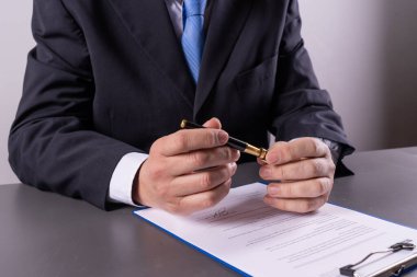 İşletme yöneticisi kalem kapağını kaldırırken aynı zamanda ofis masasında hassasiyet ve profesyonelliğe odaklanan önemli bir belgeyi imzalamaya hazırlanıyor..