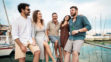 Bir grup mutlu arkadaş marinadaki yat partisinde gülüyor ve eğleniyorlar. Arkadaşlığımızı ve deniz kenarında geçirdiğimiz güzel zamanları kutluyorlar.