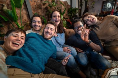 Bir grup genç arkadaş samimi bir kafede neşeli bir selfie çekiyorlar. Gülüyorlar, kucaklıyorlar ve zamanlarının tadını çıkarıyorlar. Arkadaşlığı, mutluluğu ve bağlantıyı simgeliyorlar..