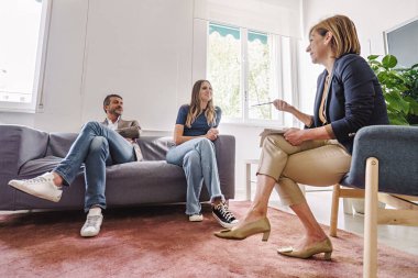 Ruh sağlığı, danışmanlık ve kişisel gelişimi tartışan iki orta yaşlı müşteriyle grup terapisi seansı düzenleyen bir terapist..