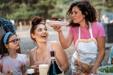 Bir grup arkadaş dışarıda barbekü için toplanır, ızgara yapar ve kırsal alanda şarabın tadını çıkarırlar. Neşeli ve rahatlatıcı bir sosyal bağ anı..