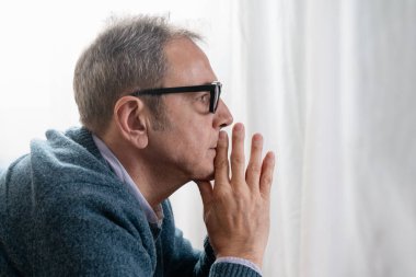 Derin düşüncelere dalmış, eli çenesinde dinlenen, ciddi ve derin düşüncelere dalmış bir adamın yakın çekimi. Karar verme, içgözlem ve zihinsel odaklanma kavramı.