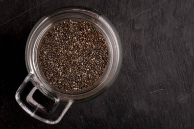 Kırsal bir arka planda cam kavanozdaki Chia tohumları. Sağlıklı organik bileşen kavramı, süper besin, doğal lif ve günlük yemeklerde sağlıklılık..