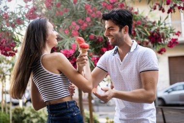 Çilekli dondurma paylaşan neşeli genç çift şehrin güneşli açık havasında, birlikte yaz havasının tadını çıkarıyorlar..