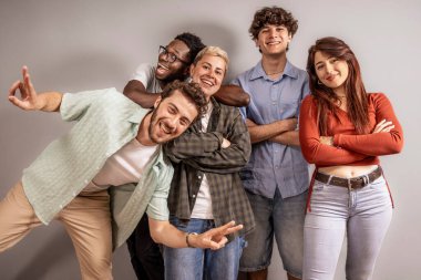 Beş kültürlü genç yetişkin gülüyor ve birlikte parlak bir stüdyoda poz veriyorlar, arkadaşlığı ve birlikteliği kutluyorlar, samimi, samimi bir grup portresiyle..