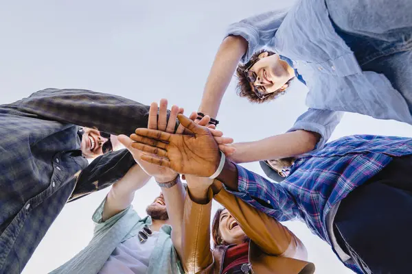 Çeşitli genç arkadaşlar aşağıdan el ele tutuşuyorlar. Birlik, işbirliği, gençlik takım çalışması ve arkadaşlık kavramı.