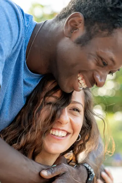 Açık havada kucaklaşan ve gülen mutlu, çeşitli genç bir çiftin samimi bir portresi. Gerçek bir aşk, şefkat ve birliktelik anı..