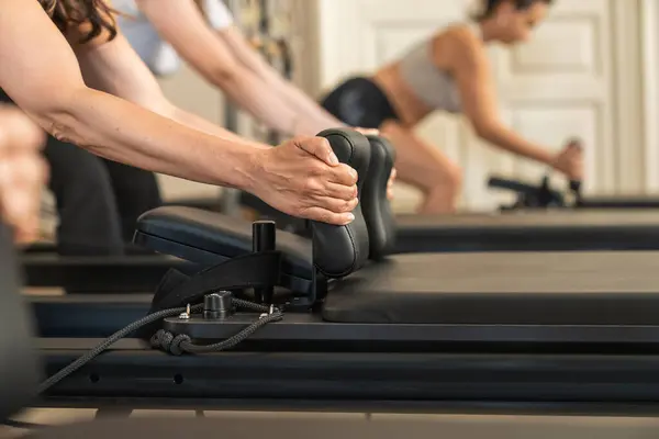 Bir grup pilates dersi sırasında, senkronize bir egzersiz yapan bir grup atletik insan. Koordineli çaba ve fitness topluluğuna odaklanın.