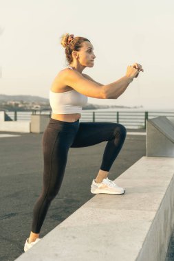 Fit bir kadın rıhtım kenarında egzersiz yaparken adım egzersizi yapıyor..
