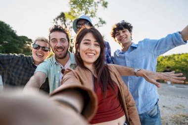 Neşeli bir macerada selfie çeken gülümseyen Gen-Z arkadaşları, kameraya doğru uzanan kollar; seyahat, arkadaşlık ve sosyal medya yaşam tarzı kavramı.
