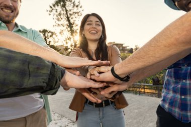 Çeşitli arkadaş ya da meslektaşlardan oluşan bir ekip ellerini gülümseyen genç bir kadının etrafında bir çember şeklinde bir araya getiriyor. Desteği, dahil olmayı, takım çalışmasını ve sıcak bir karşılamayı simgeliyor..